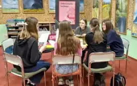 Pięć klubowiczek siedzi przy stole i dyskutuje o książce.