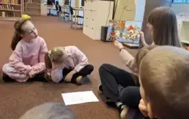 Pani bibliotekarka czyta dzieciom książkę.