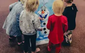 Maluszki &bdquo;karmią&rdquo; Olafa śnieżnymi kulami &ndash; piłeczkami pinpongowymi.