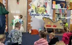 Kobieta z dziećmi przyczepiają ozdobione papierowe choinki do drzwi.