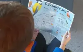 Uczestnik trzyma w rękach ulotkę.