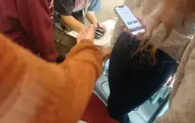 Uczniowie rozwiązują zadania, jedna z nich trzyma telefon z włączoną grą