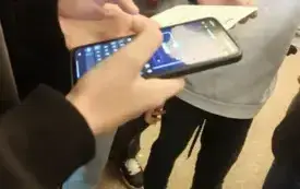 Uczeń trzyma telefon, na kt&oacute;rym wyświetla się gra