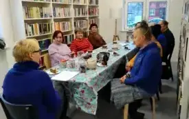 Uczestnicy spotkania zadają pytania Małgorzacie Murowickiej-Kozickiej na temat herbaty. Siedzą przy stole, na kt&oacute;rym są dzbanki z r&oacute;żnymi rodzajami herbat, talerzyki, słodycze