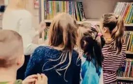 Dzieci oglądają książki na regałach.