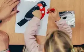 Dziewczynka doczepia plastelinę w odpowiednich miejscach.