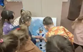 Dzieci karmią Olafa piłeczkami pingpongowymi, kt&oacute;re udają śnieżne kule.