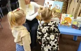 Bibliotekarka czyta dzieciom książkę pt. &bdquo;Dziadkowie&rdquo;.  