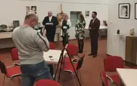 Otwarcie wystawy. Zgromadzeni uczestnicy wystawy pt. "Rzemiosło gliny na przestrzeni wiek&oacute;w w Gminie Witnica". W pomieszczeniu panuje jasność. W tle widoczne dzbanki.