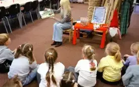 Bibliotekarka czyta dzieciom książkę podczas zimowych zajęć w bibliotece.