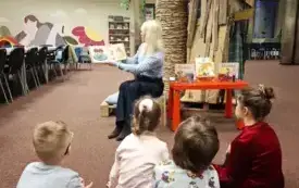 Bibliotekarka czyta dzieciom książkę pt. &bdquo;Dziadkowie&rdquo;.