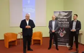 Stojący na środku sali dyrektor przedstawia stojącego po prawej stronie Marcelego Tureczka. Obok nich Grzegorz Urbanek, z tyłu rollup z nazwą i logo spotkania z cyklu "Nowa Marchia"
