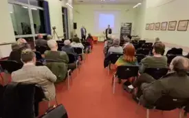 Na pierwszym planie publiczność zgromadzona w sali, w tle Marceli Tureczek i Grzegorz Urbanek