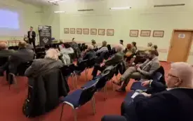 Na pierwszym planie publiczność zgromadzona w sali, w tle Marceli Tureczek i Grzegorz Urbanek
