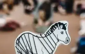 Grupa dzieci nawleka wł&oacute;czkę na zalaminowane zebry.
