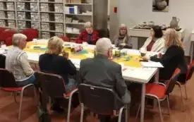 Przy duzym stole siedzą klubowicze- siedem os&oacute;b i rozmawiają o książce