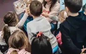 Bibliotekarka czyta dzieciom książkę z otwieranymi okienkami. 