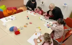 Uczestnicy warsztat&oacute;w siedzą przy stołach oraz wykonują prace plastyczne w oparciu o dostępne materiały (pomoce dydaktyczne).