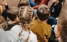 Bibliotekarka czyta dzieciom książkę na dywanie.