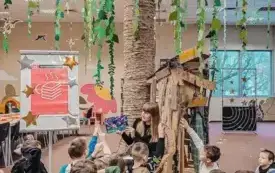 Dzieci słuchają książki czytanej przez Panią Bibliotekarkę.