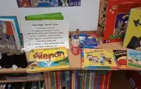 Na regale wystawione są kolorowe książeczki o kotach. W środku ekspozycji jest informacja o Dni Kota.