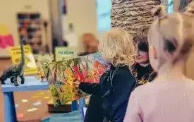 Bibliotekarka czyta dzieciom książkę o dinozaurach.