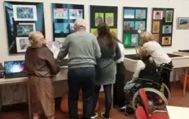 Kilka os&oacute;b patrzy na wystawę.