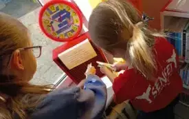 dwie dziewczynki wkładające listy do skrzynki na parapecie