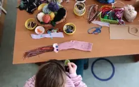 widok dziewczynki z g&oacute;ry siedzącej przy stole z akcesoriami krawieckimi