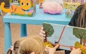 Dzieci słuchają książki czytanej przez panią bibliotekarkę.