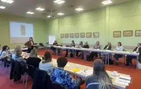 Bibliotekarki siedzą przy stole słuchają z uwagą trenerki.