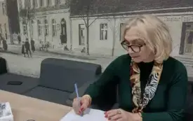 Kobieta wśr&oacute;d publiczności w pomieszczeniu biblioteki.