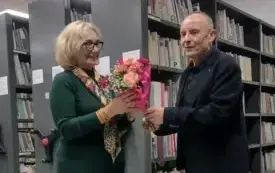 Mężczyzna wręcza bukiet kwiat&oacute;w kobiecie.