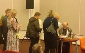Wiesław Ochman podpisujący zakupione książki