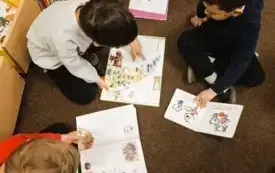 Dzieci siedzą na podłodze i oglądają książki.