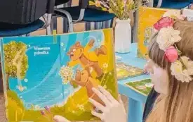 Pani bibliotekarka czyta uczestnikom spotkania wiersz.