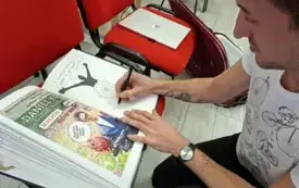 Mężczyzna dokonuje wpisu do księgi pamiątkowej.
