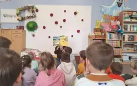 Prowadząca zajęcia czyta dzieciom książkę 