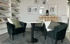 Dwa fotel przy stoliku w przestrzeni bibliotecznej.