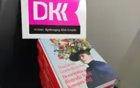 Na czarnym krześle leży stos książek Magdaleny Grzebałkowskiej &bdquo;Dezorientacje. Biografia Marii Konopnickiej&rdquo;. Na g&oacute;rze stosu leży logo Dyskusyjnego Klubu Książki. W tle za krzesłem widać białą ścianę.