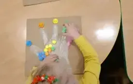 Dzieci segregują kolorowe pomponiki. 