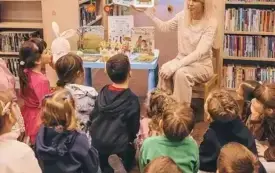Bibliotekarka czyta dzieciom książkę o wiośnie.