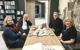 Cztery osoby siedzą przy podłużnym stole.