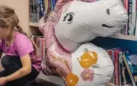 Dziewczynka segreguje pompony i koraliki.