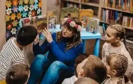 Bibliotekarka czyta dzieciom książkę przy Pani Wiośnie.