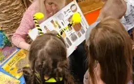 Bibliotekarka czyta dzieciom książkę o pszczołach.