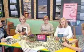 Przy stole siedzi pięć czytelniczek. Za nimi na ścianie wiszą czarne plansze z fotografiami.