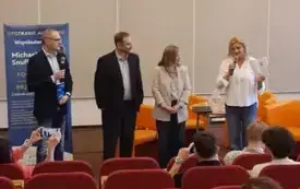 Przed publicznością siedzącą na czerwonych krzesłach stoją (od lewej) Tomasz Terefenko, Michael Snuffer, Mary Snuffer oraz Agnieszka Przybył.