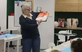 Kobieta stoi z książeczką w ręce.