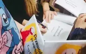 Ewa Pawlak wpisuje dedykacje do książek dla młodych czytelnik&oacute;w.